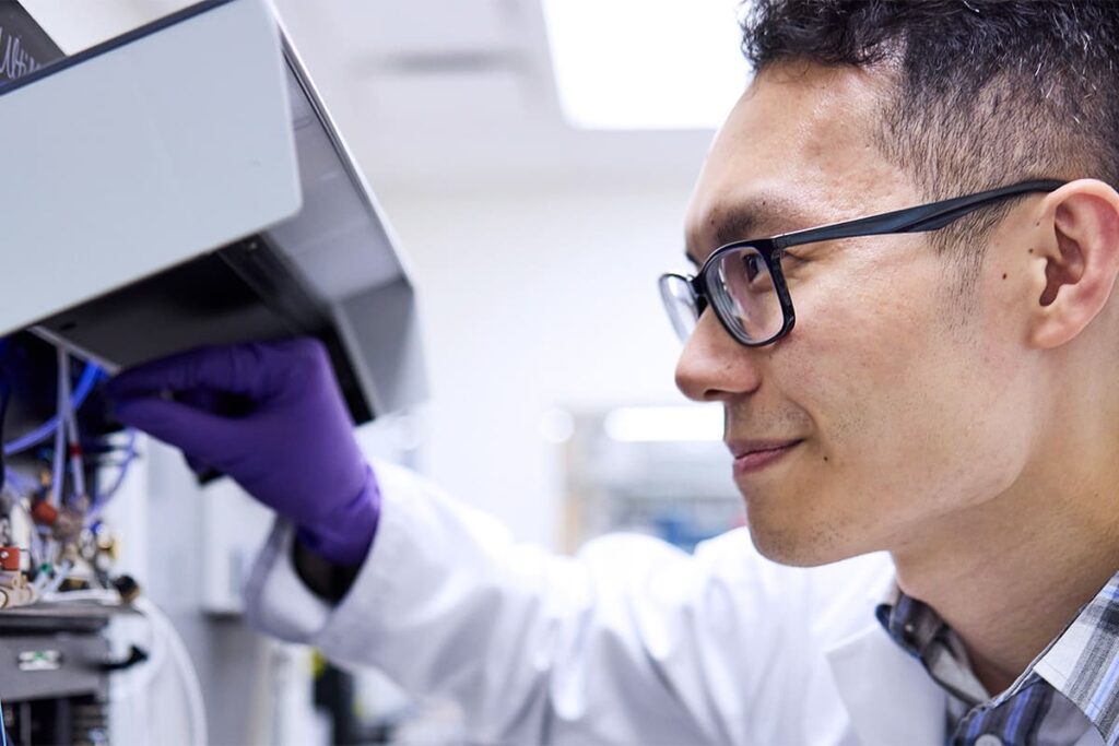 researcher with glasses looking at equipment in lab